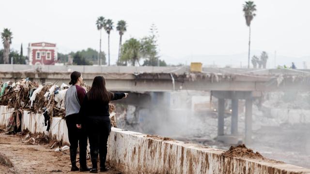 Dos mujeres observan la demolición del puente del ferrocarril en Paiporta, Valencia, tras el paso de la DANA.