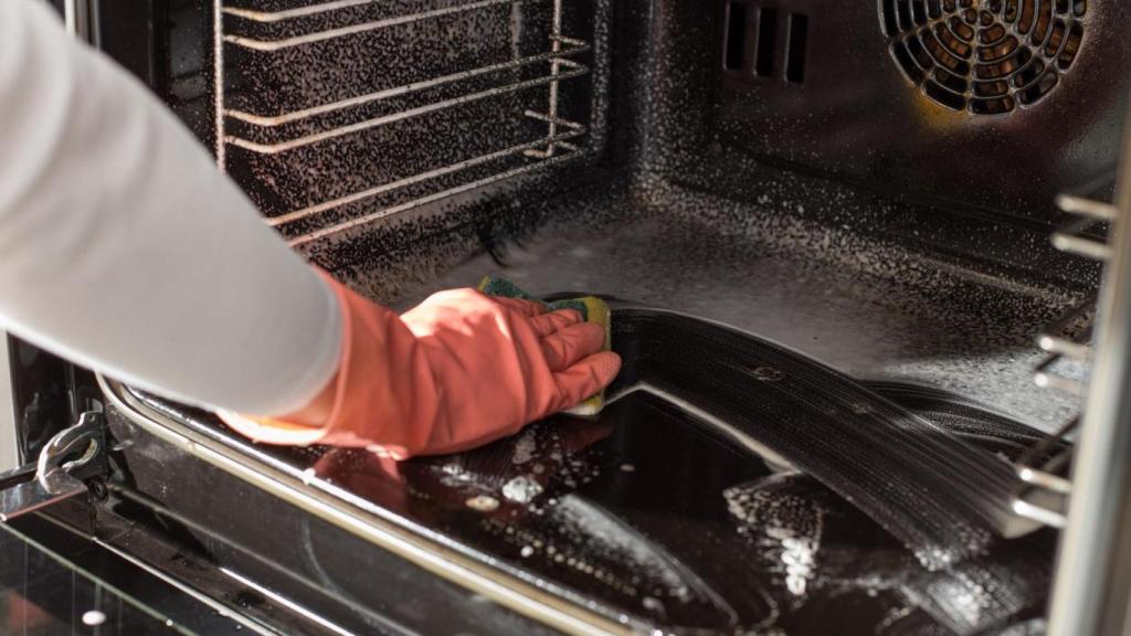 Una persona limpiando un horno.