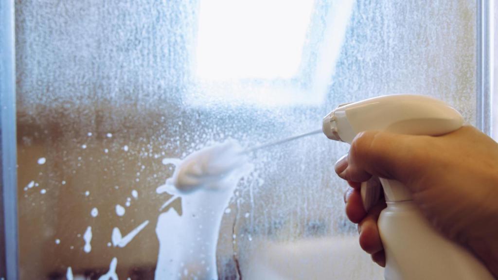 Una persona limpiando una ducha.