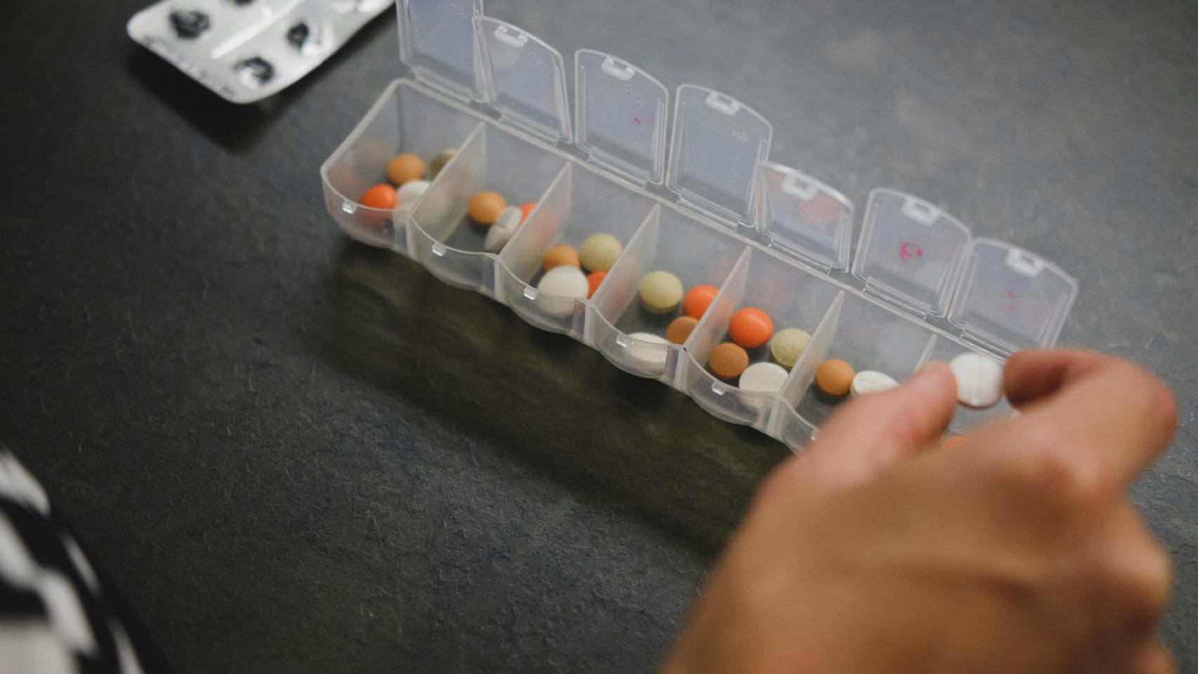 Una mujer usando un pastillero para repartir las medicinas.