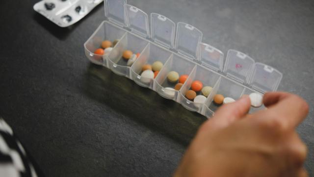 Una mujer usando un pastillero para repartir las medicinas.