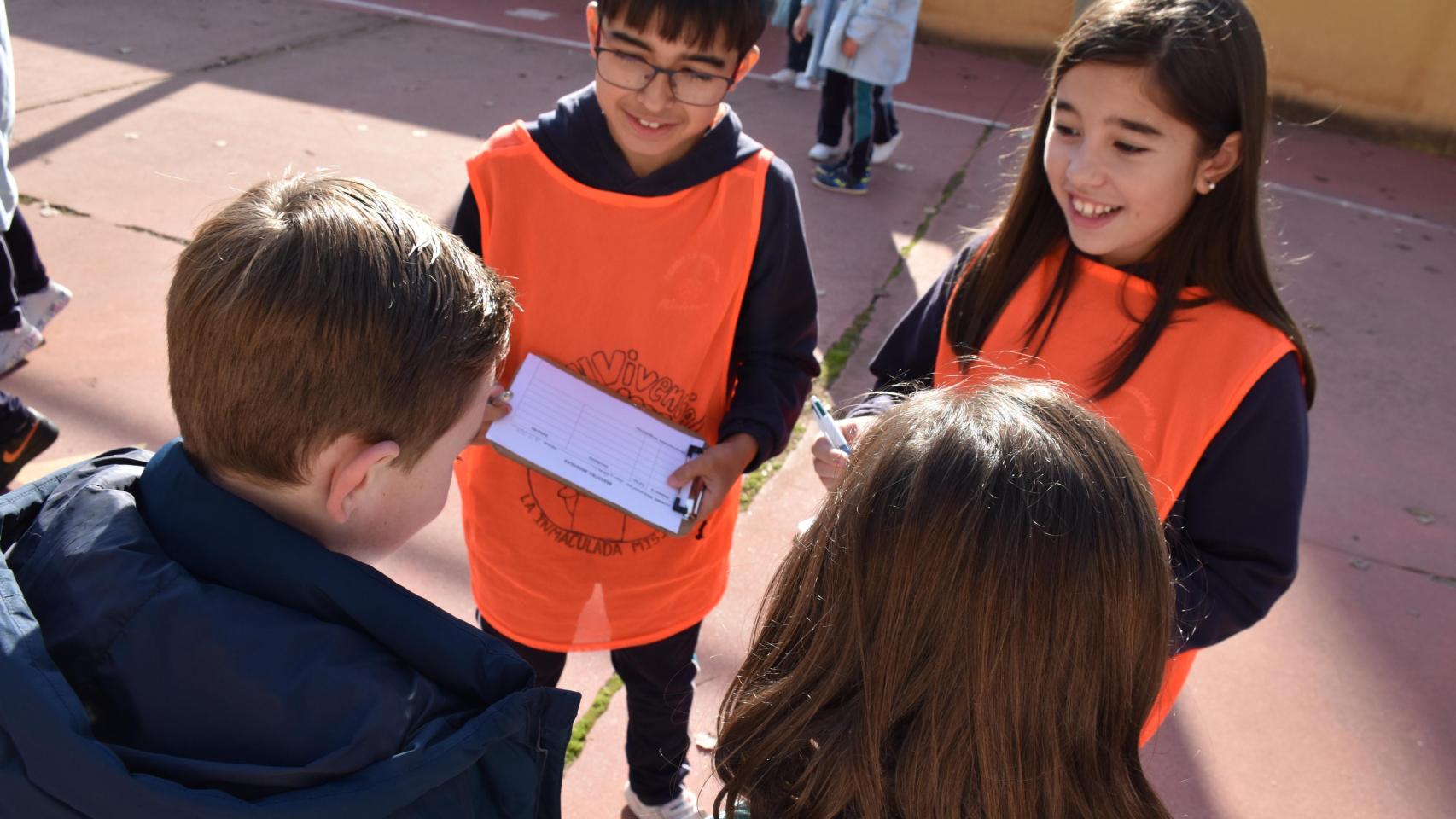 Una pareja del último curso del centro ayudando a otros alumnos a la hora de recreo