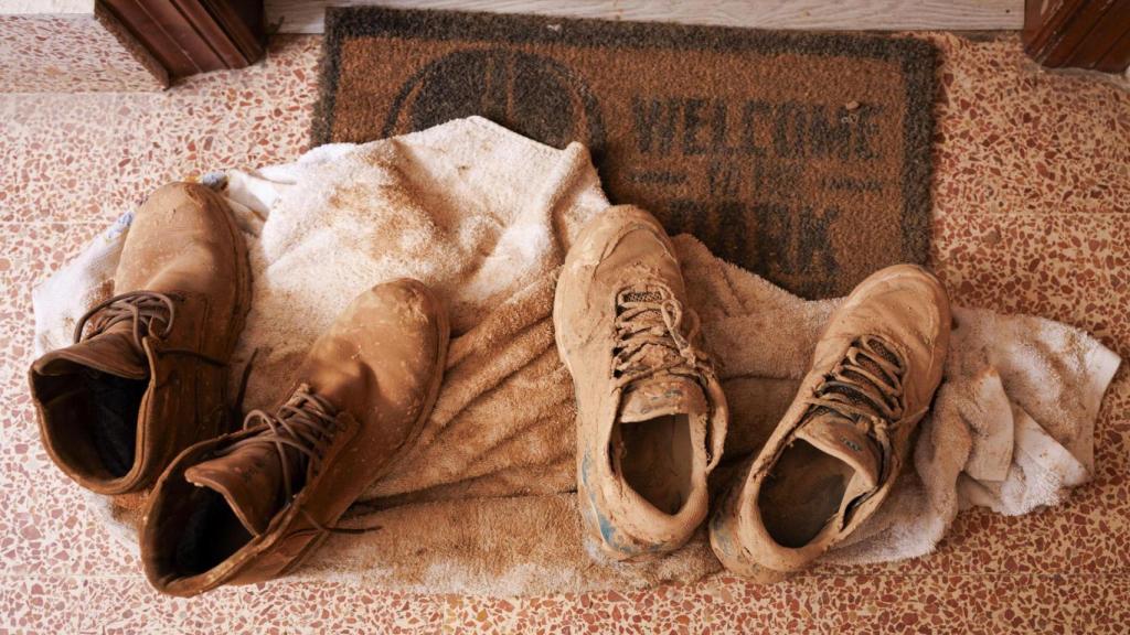 Fotografía de zapatillas llenas de barro en la entrada a una vivienda en Paiporta.