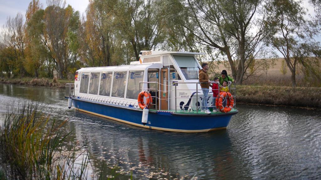 Arriba, el barco Juan de Homar surcando el tramo palentino del Canal de Castilla