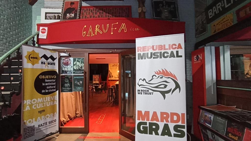 Acceso a la sala Garufa con rótulos de otros locales y actividades musicales.