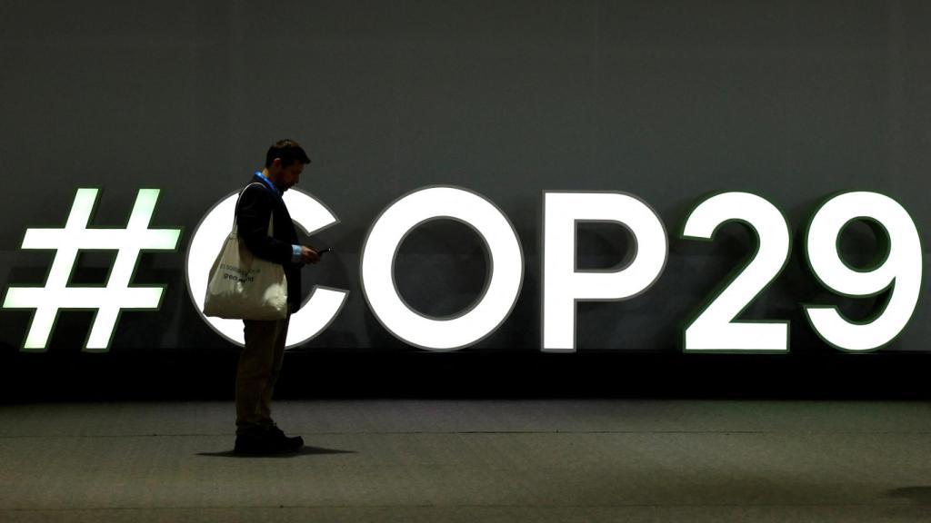 Un hombre frente al logo de la COP29 durante las negociaciones en Bakú.