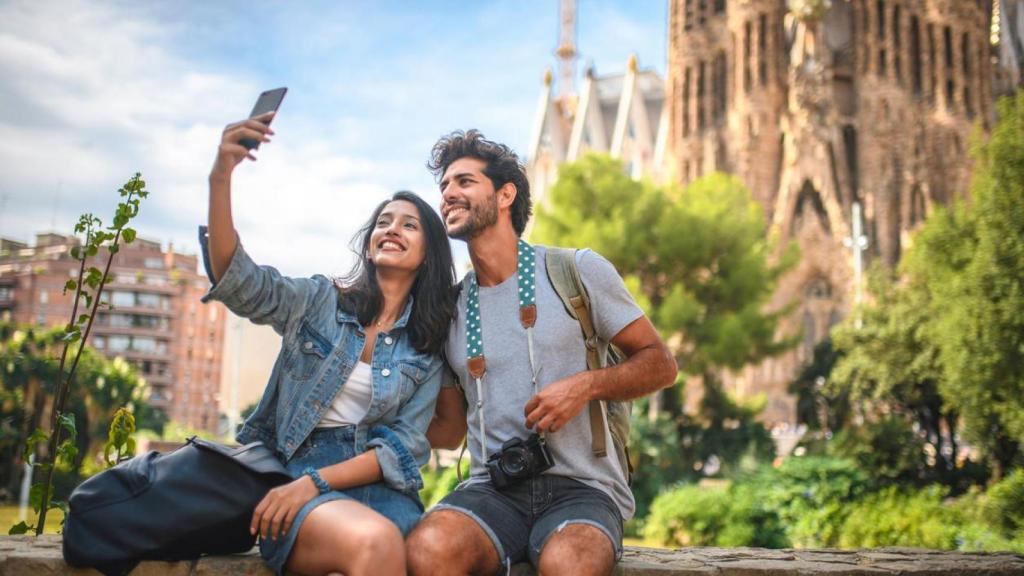 Una pareja sacando una foto en la Sagrada Familia para compartir en redes.