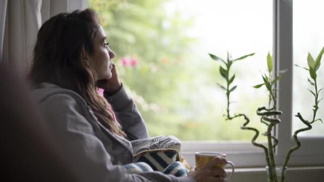 Mujer preocupada mirando por la ventana.