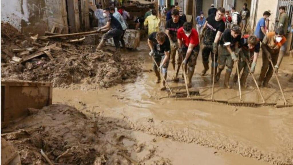 Un grupo de voluntarios tratando de retirar el lodo de una calle de Masanasa.