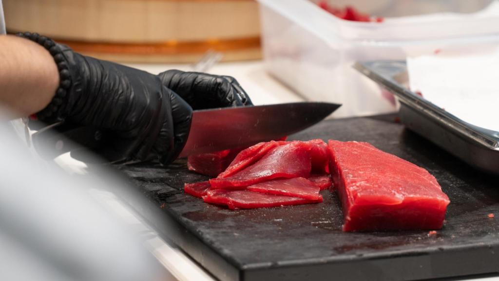 Una cocinera trabajando el atún en la cocina abierta de Almadraba Experience.