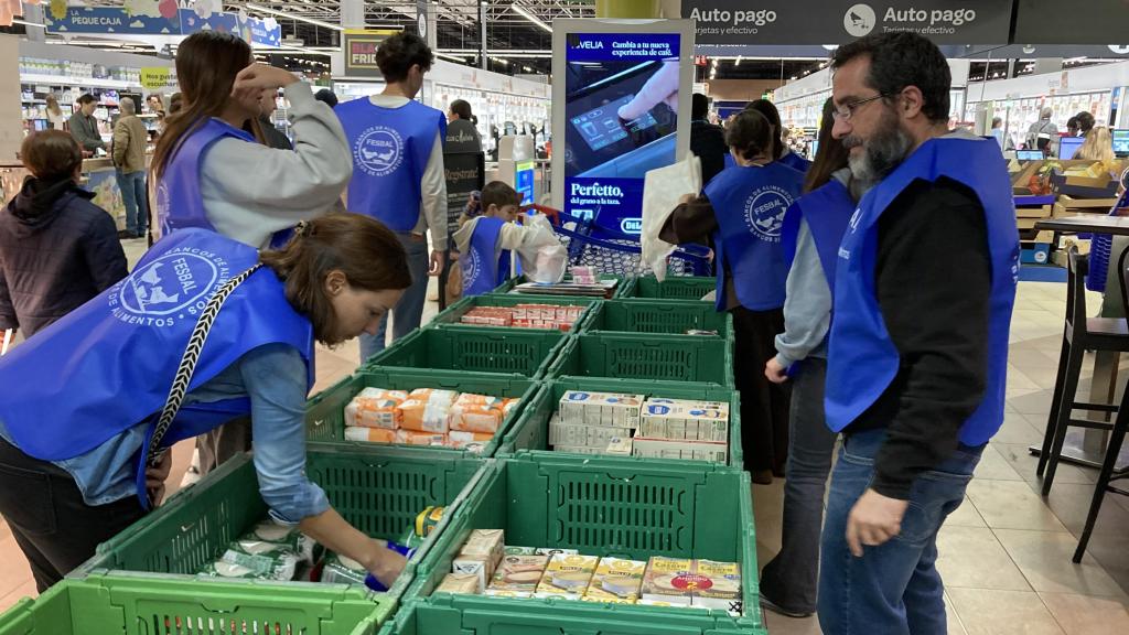 Víctor Acosta y otros voluntarios colocan la comida donada este sábado en un centro comercial de Alcobendas.