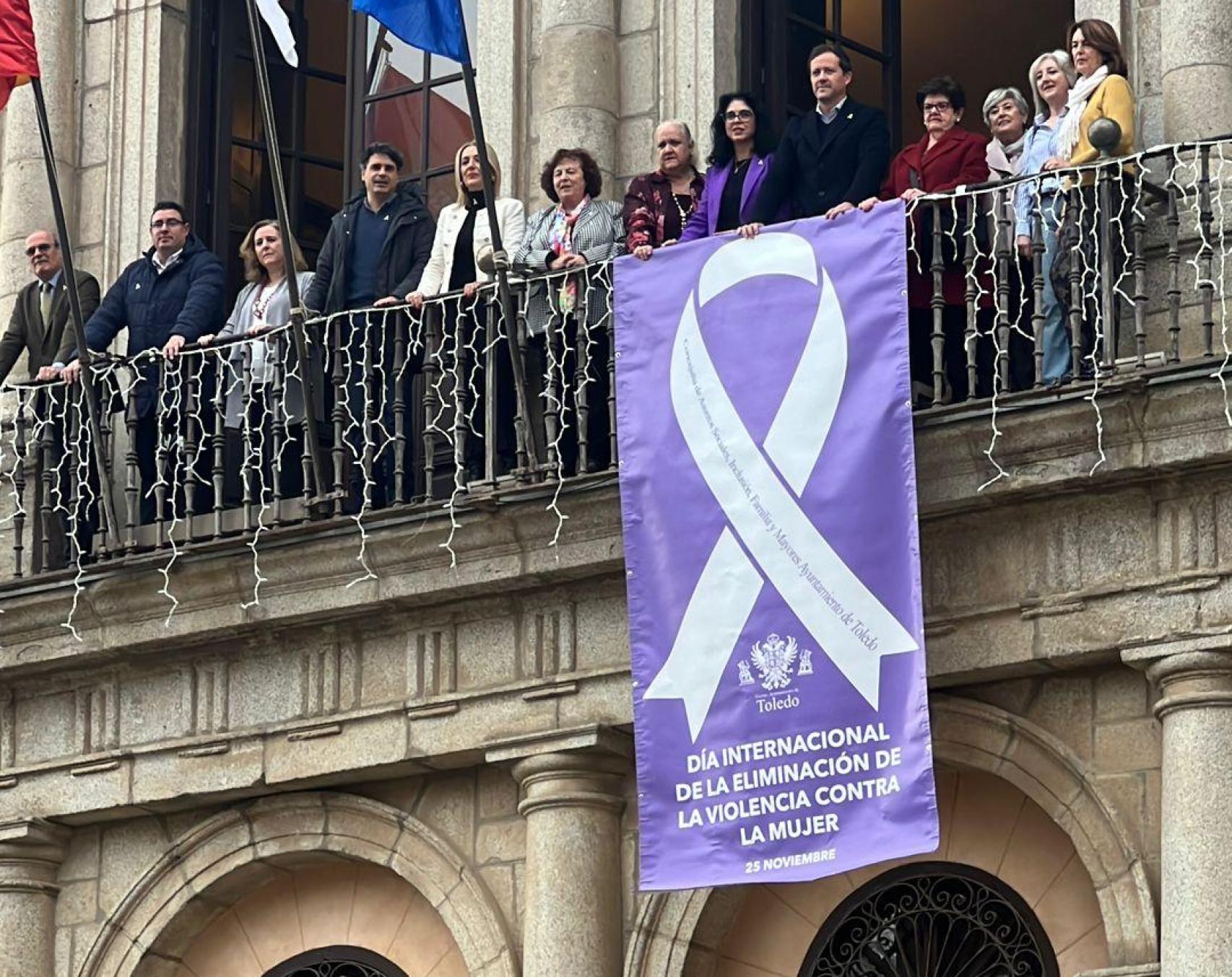 El alcalde, Carlos Velázquez, junto concejales del PP y Vox, y miembros del Consejo de la Mujer desplegó el lazo blanco contra la violencia machista en la balconada del Ayuntamiento de Toledo.