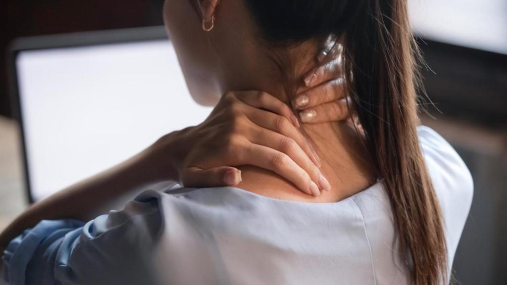 Imagen de archivo de una mujer que se queja de dolor frente a su ordenador.