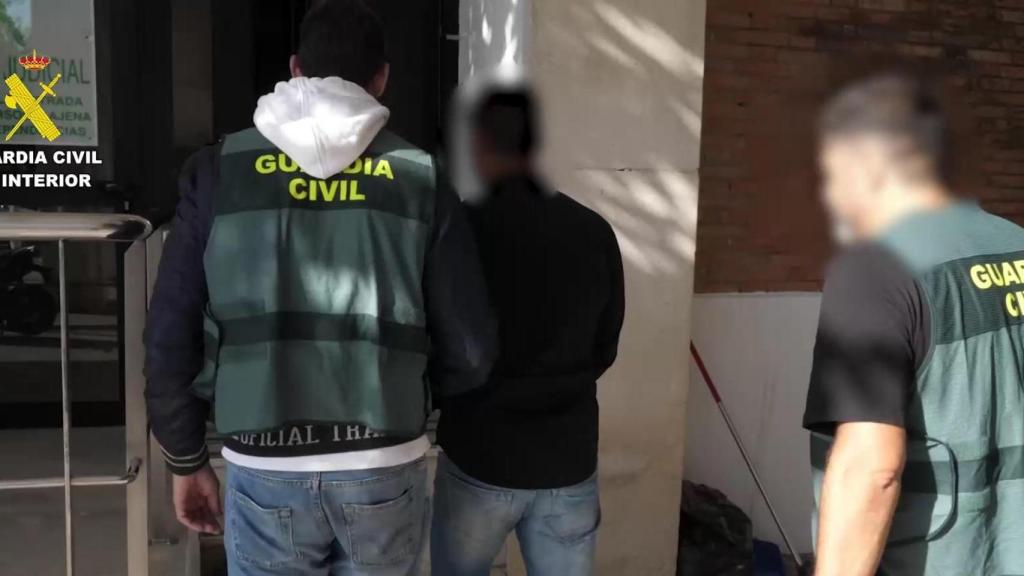 Dos agentes de la Guardia Civil custodian al detenido por el crimen de Umbrete.