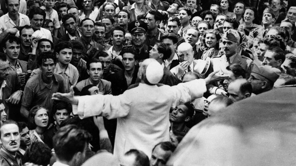 El papa Pío XII rodeado de fieles y con los brazos levantados en señal de bendición el 13 de agosto de 1943, durante los bombardeos aliados de Roma.