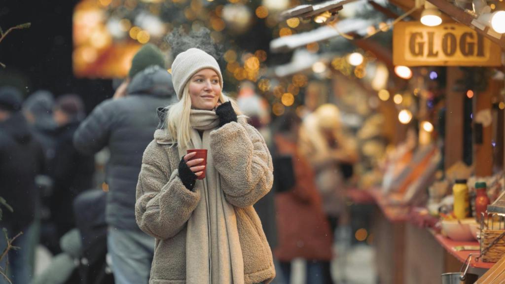 Mujer paseando en invierno por un mercado navideño