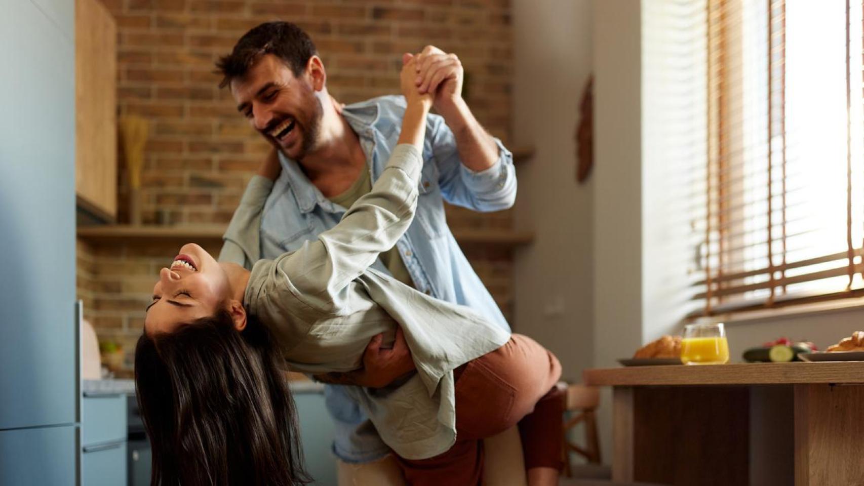 Pareja riendo mientras baila en la cocina.