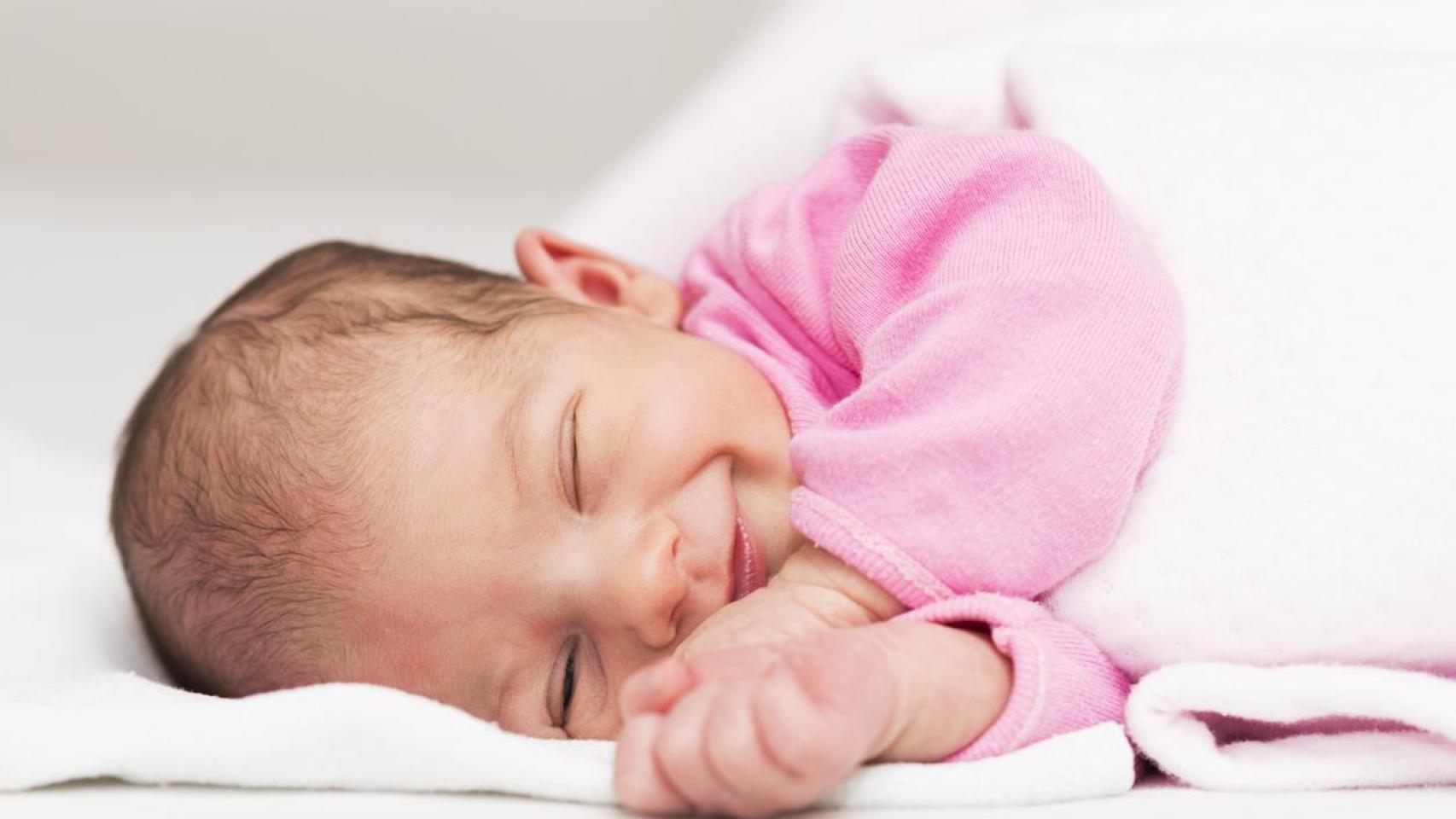 Bebé recién nacido con una sonrisa adorable.