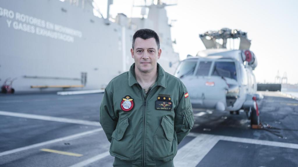 El Capitán Jorge Alejandro Castillo Vila posa sobre la pista del LHD Juan Carlos I, frente a un Sikorsky SH-60 'Seahawk', el helicóptero naval que pilota.