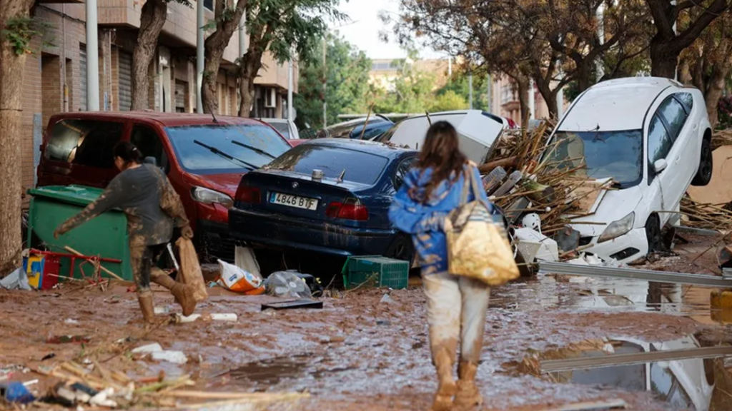 Varias personas caminan entre el lodo acumulado en las calles en Catarroja.