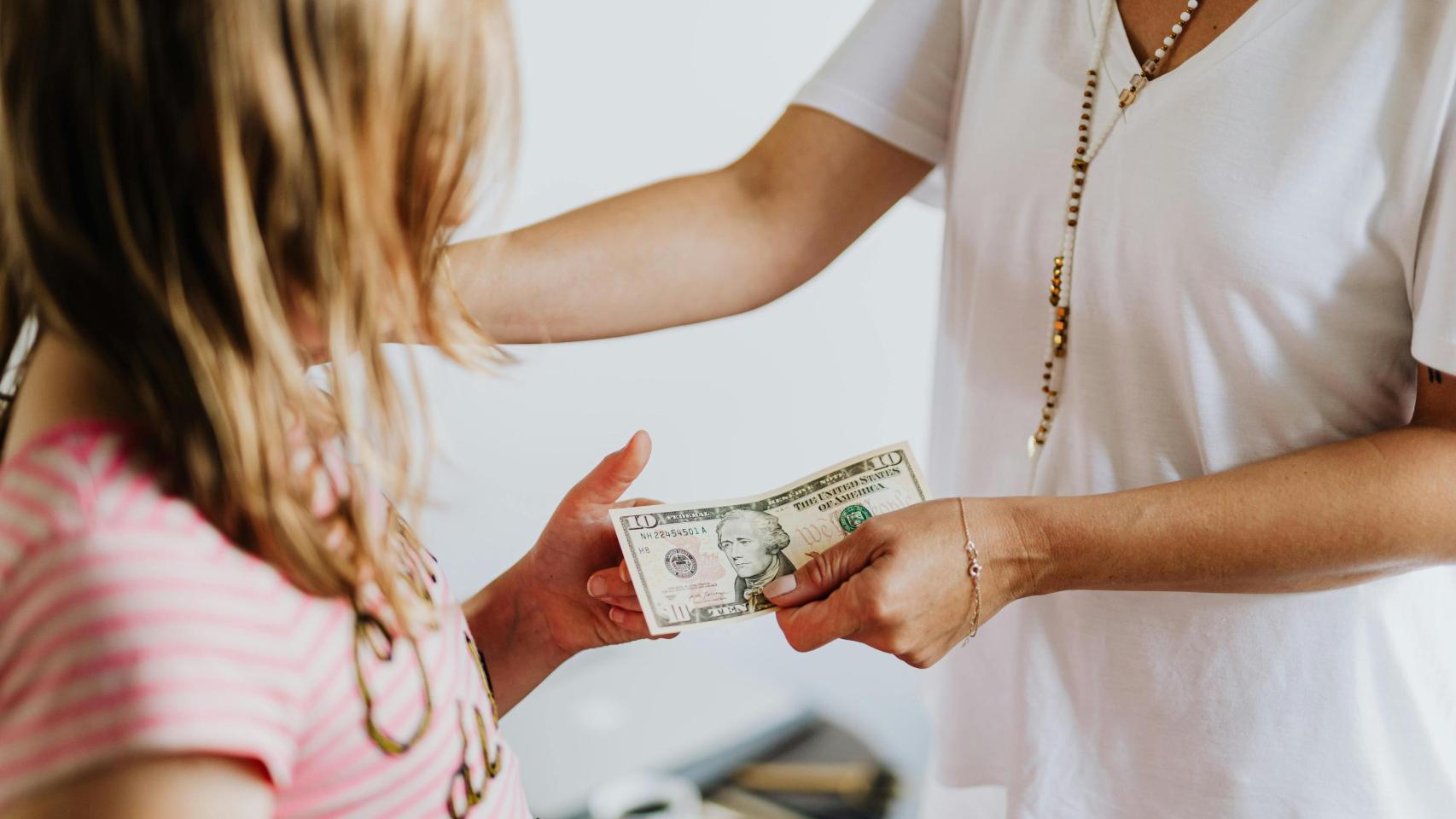 Mujer dando dinero a una niña