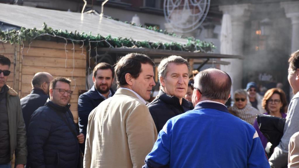 Alfonso Fernández Mañueco y Alberto Núñez Feijóo conversan con un hombre en la Plaza Mayor de Valladolid