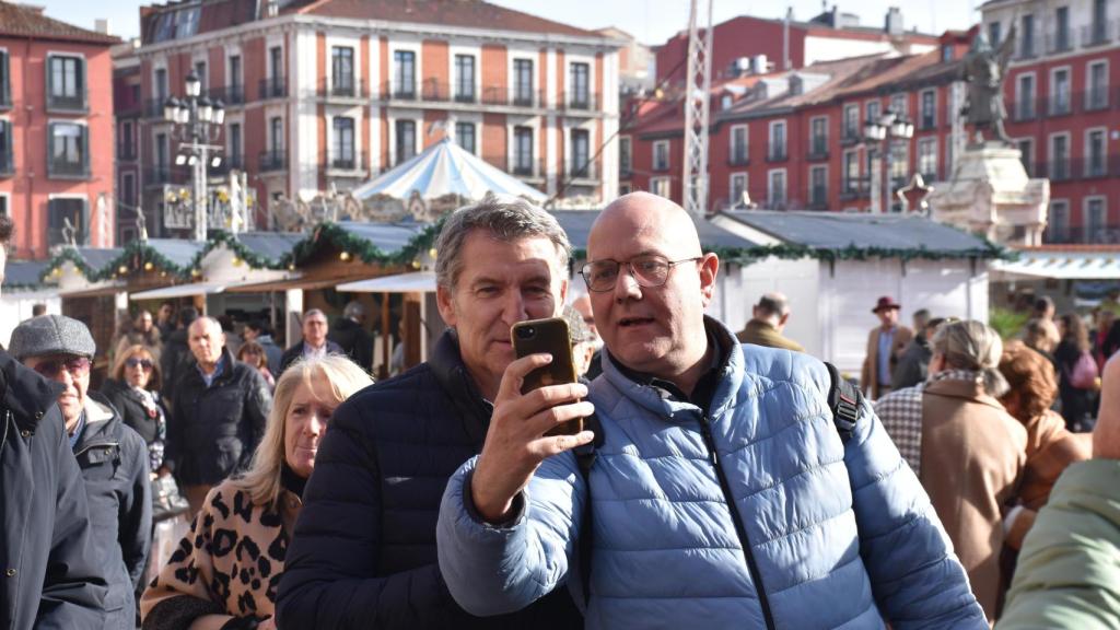 El líder del Partido Popular (PP), Alberto Núñez Feijóo, se hace un 'selfie' con un hombre en el mercado navideño de la Plaza Mayor de Valladolid