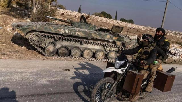 Opositores pasan junto a un tanque capturado del ejército sirio.