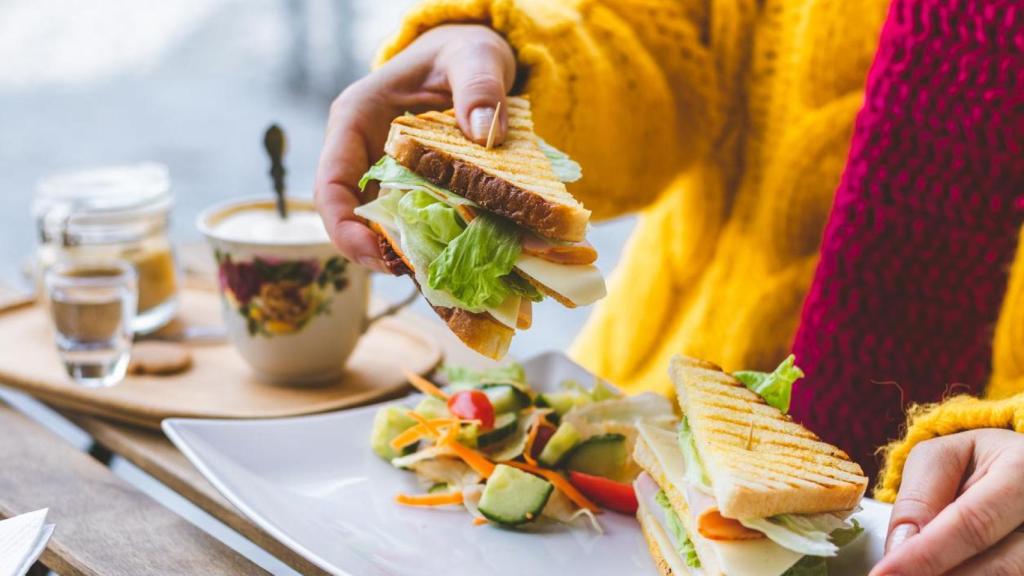 Mujer comiendo un sándwich vegetal.