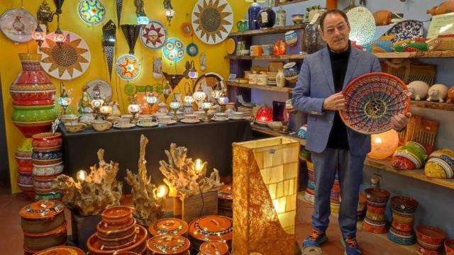 Adolfo López muestra objetos que vende en su tienda de artesanía de A Coruña, Tierra de Fuego.