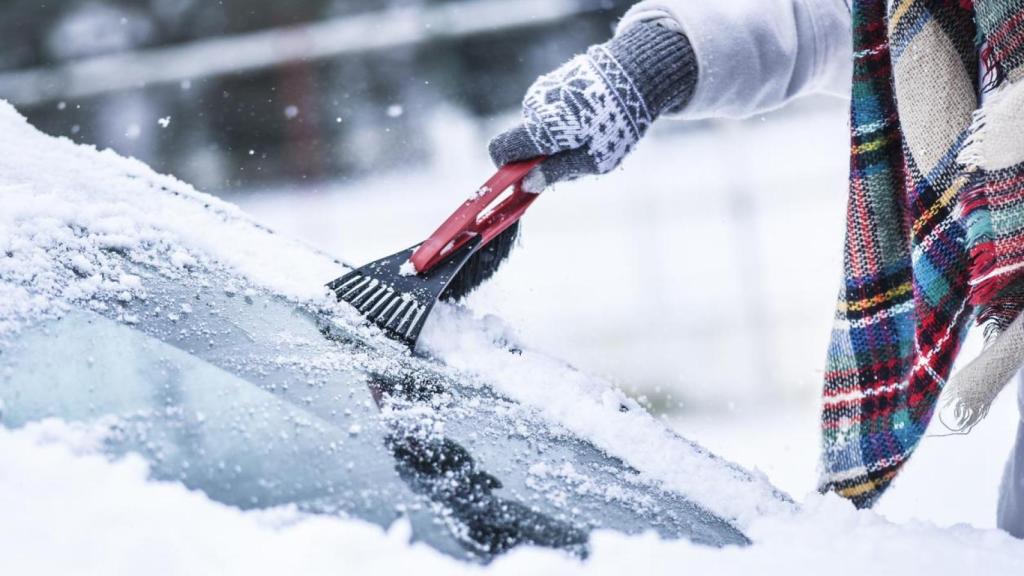 Mujer limpiando el hielo del parabrisas.