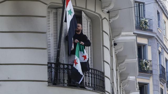 Una persona cambia la bandera siria por la nueva rebelde en la embajada de Siria en Madrid.