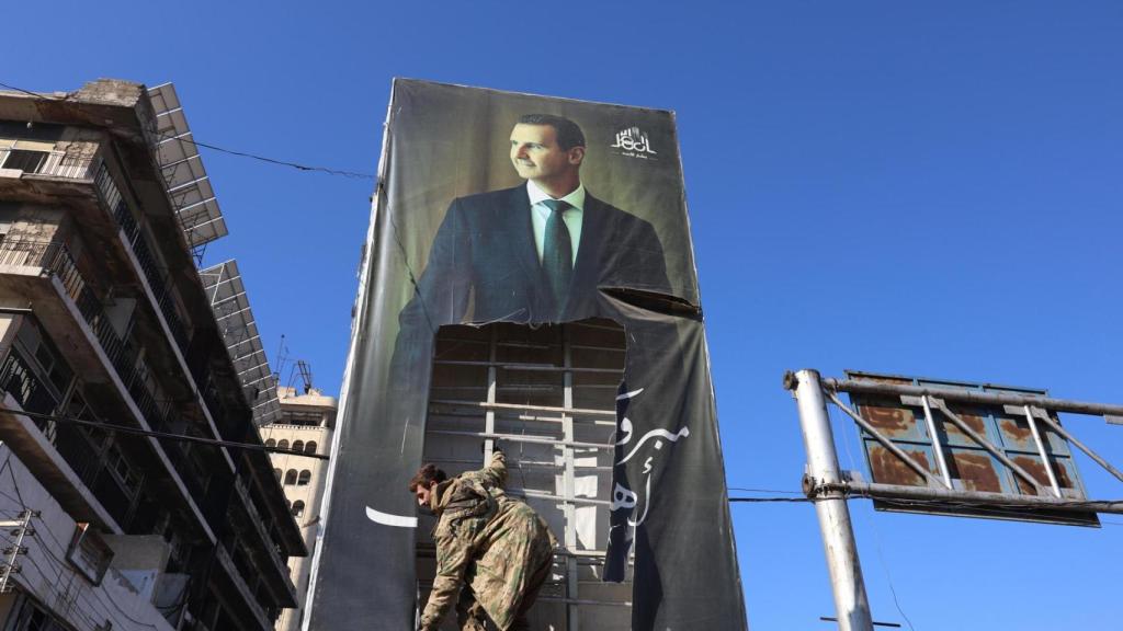 Un combatiente de la oposición rompe un enorme retrato del presidente sirio Bashar al-Assad en Alepo.