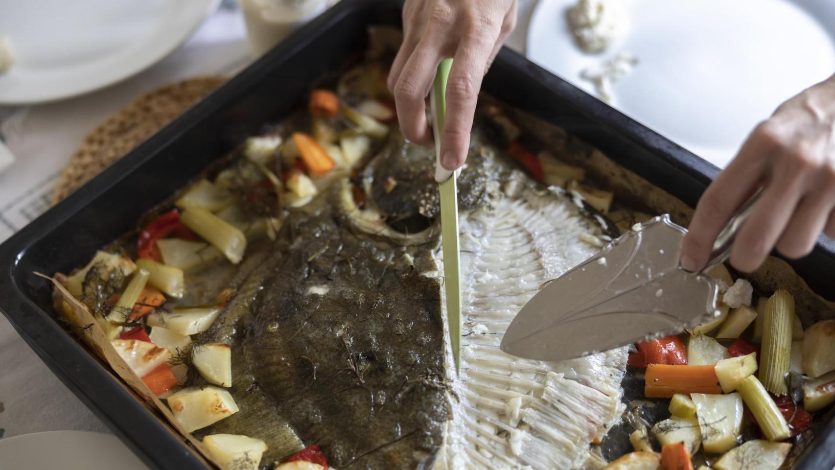 Una persona prepara un rodaballo al horno para servir