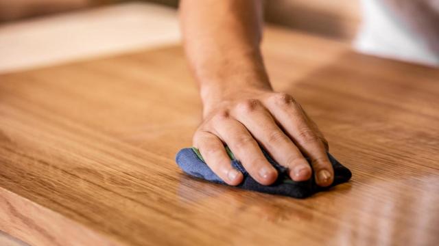 Un joven aplicando aceite en una superficie de madera.