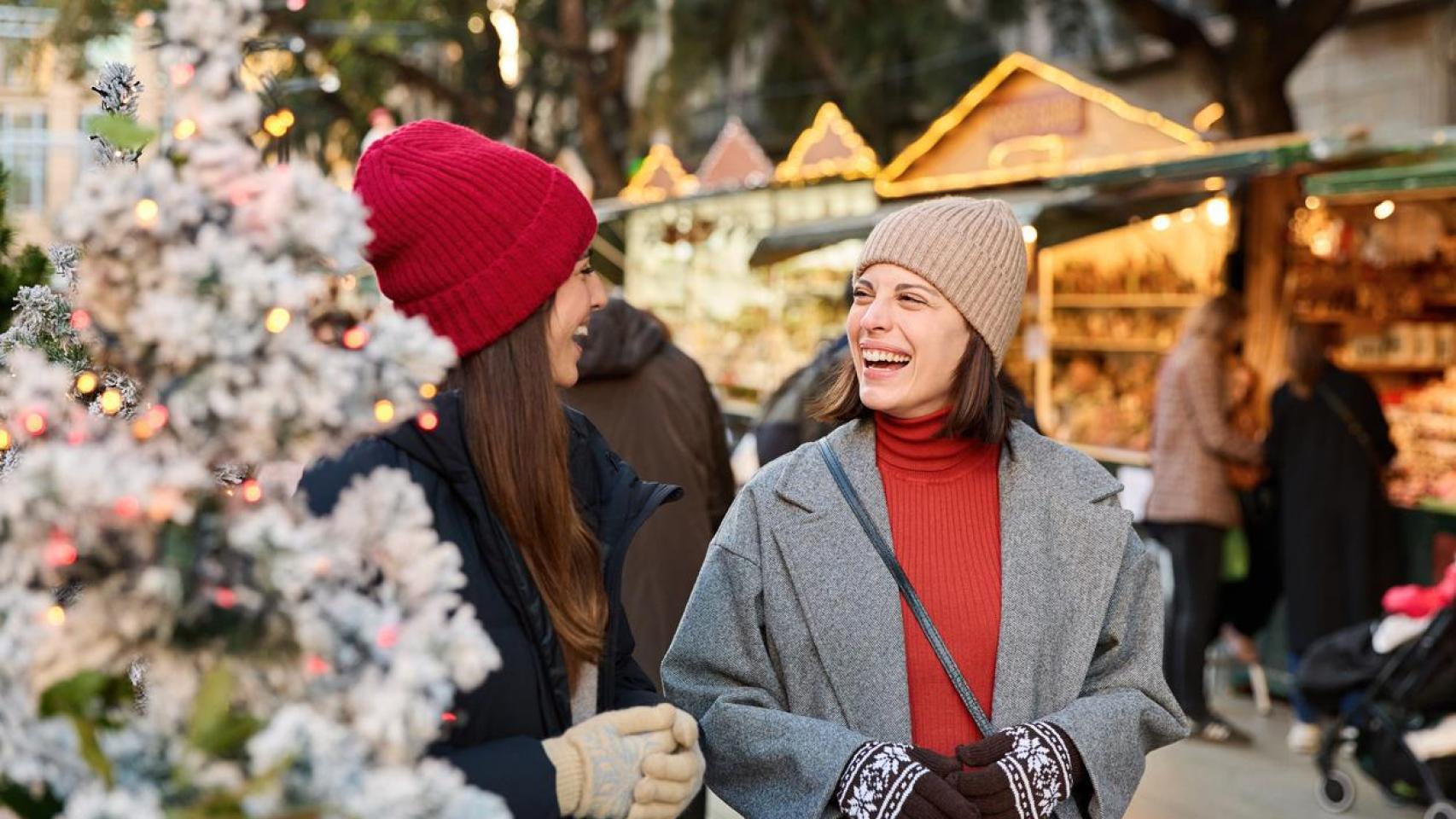 Amigas paseando por un mercadillo navideño.