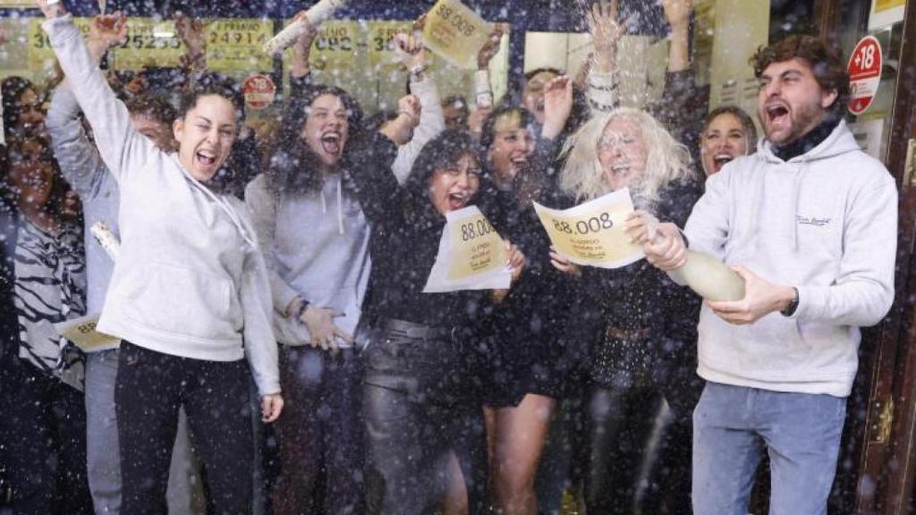 Personas celebrando el Gordo de la Lotería de Navidad en una administración.