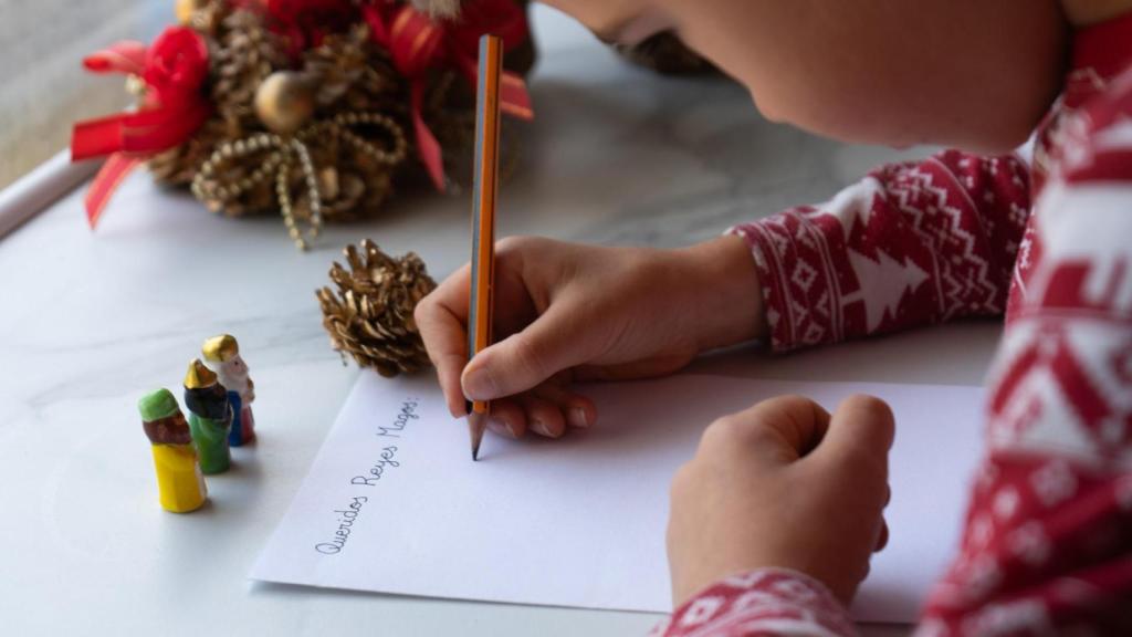 Un niño escribe la carta a los Reyes Magos.