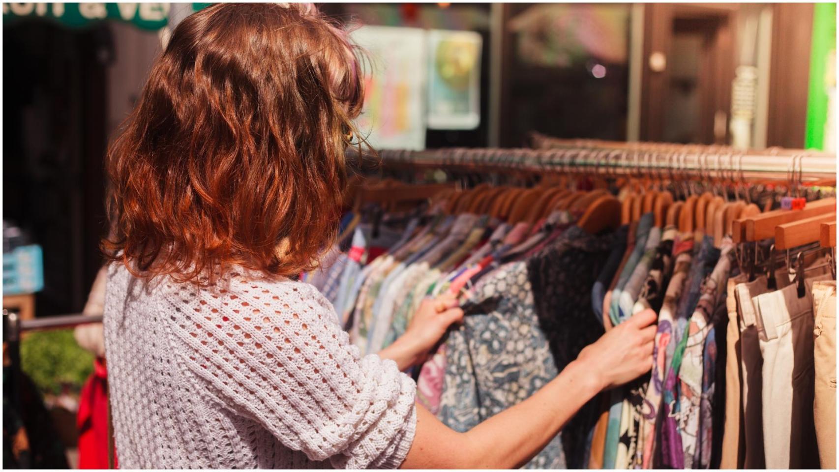 Una mujer busca una prenda de ropa en un mercado.