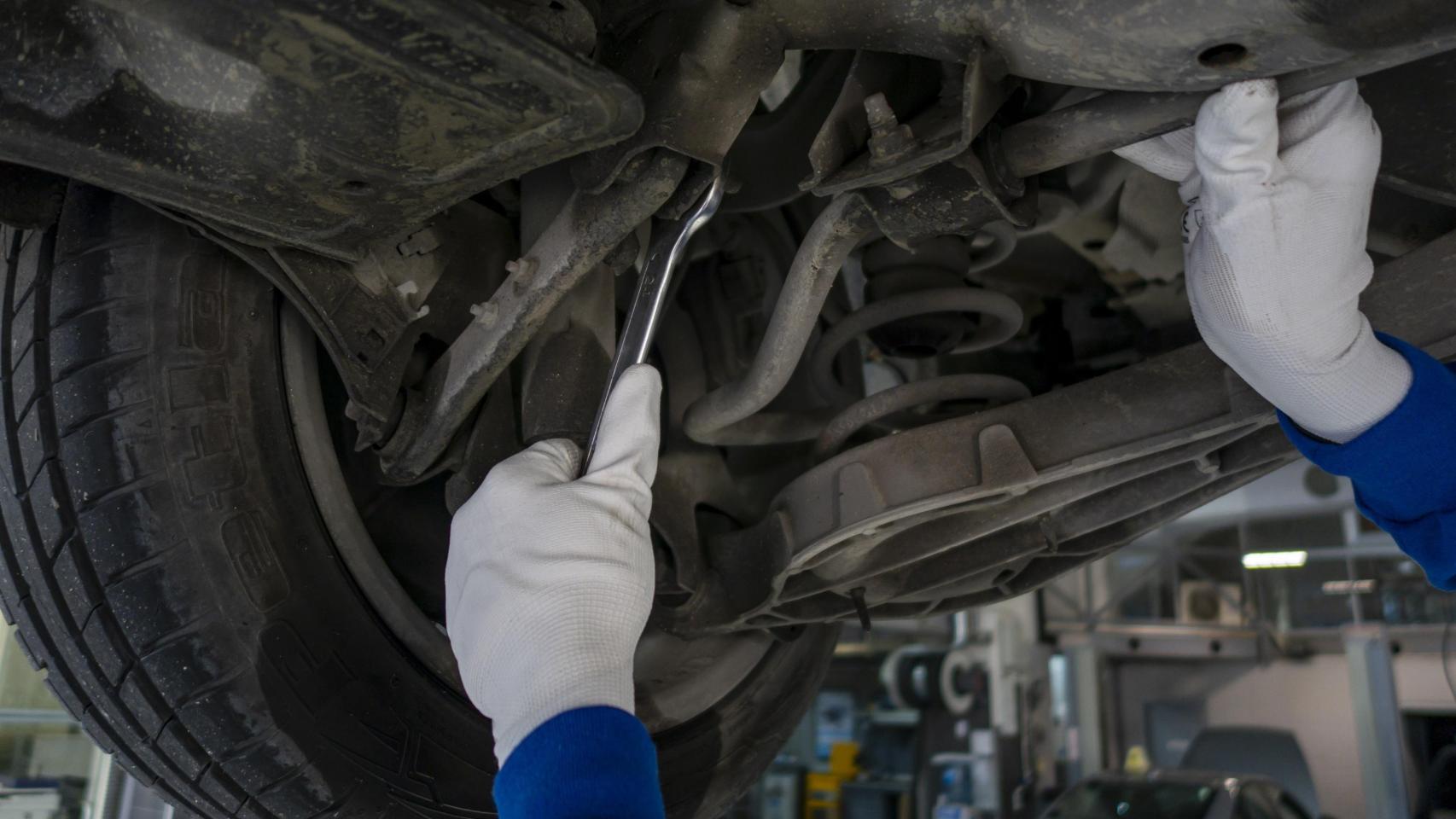 Imagen de un mecánico con un coche.