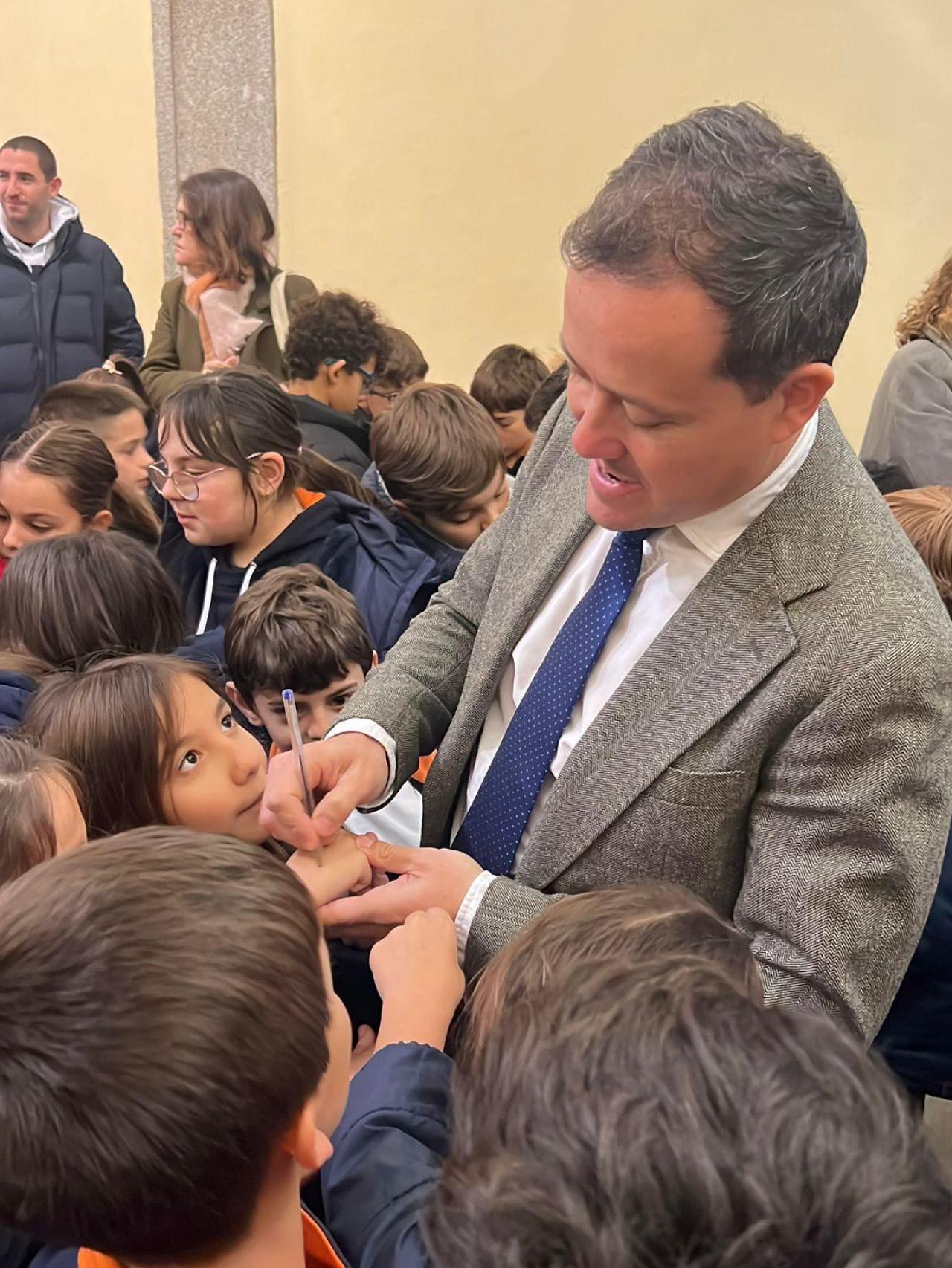 El alcalde de Toledo, Carlos Velázquez, firma autógrafos a los alumnos del colegio Divina Pastora durante la inauguración del belén municipal.