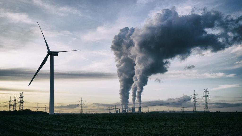 Imagen de archivo de aerogeneradores frente a una central eléctrica de carbón.