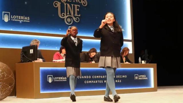 Dos niñas de San Idelfonso mostrando uno de los números premiados en la Lotería de Navidad.