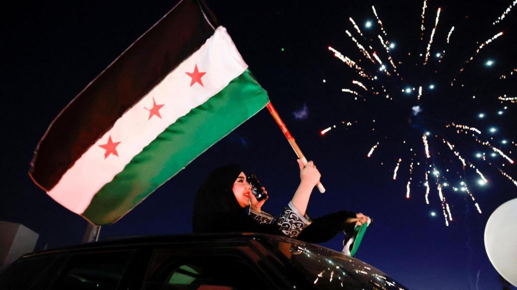 Una mujer sostiene la bandera adoptada por los nuevos gobernantes sirios tras la caída de Asad.