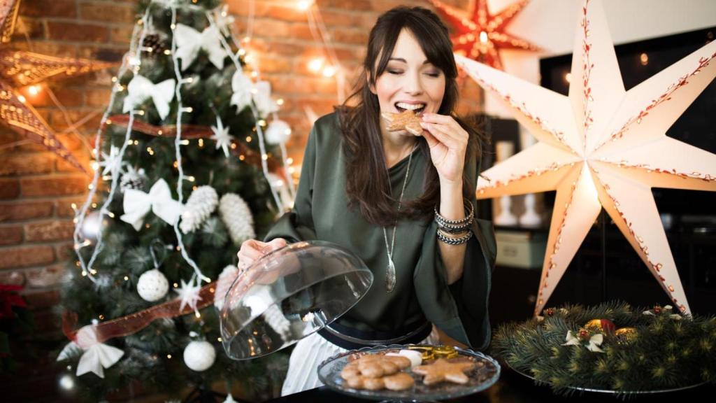 Mujer comiendo un dulce navideño.