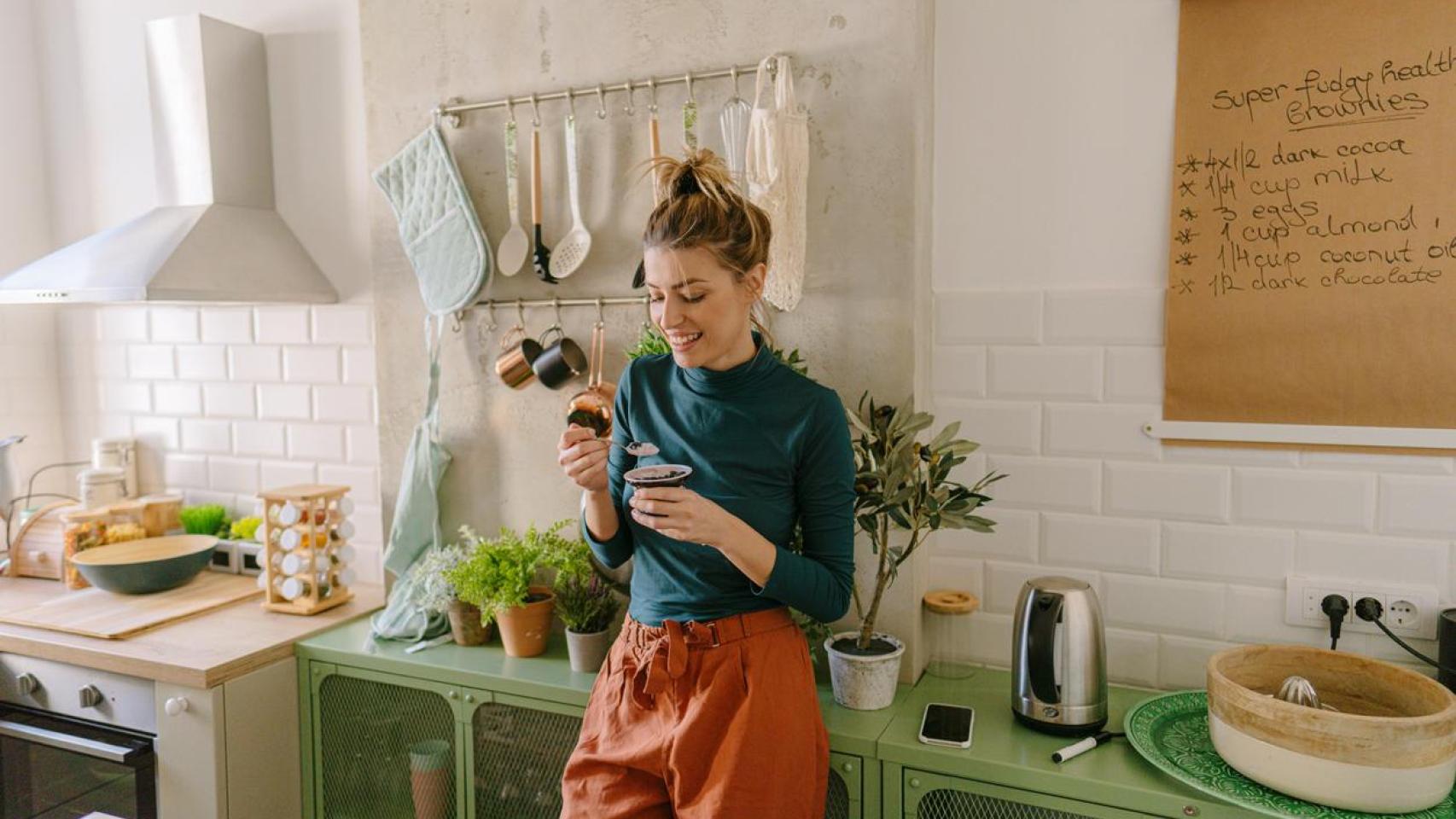 Mujer comiendo en la cocina.