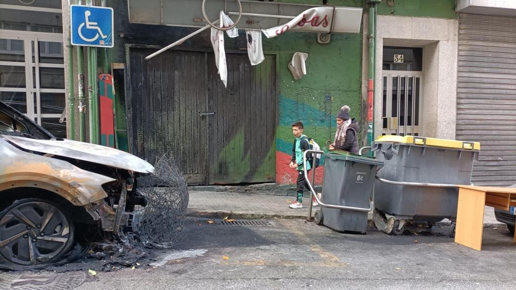 El coche calcinado y la fachada del edificio afectada en Monelos.