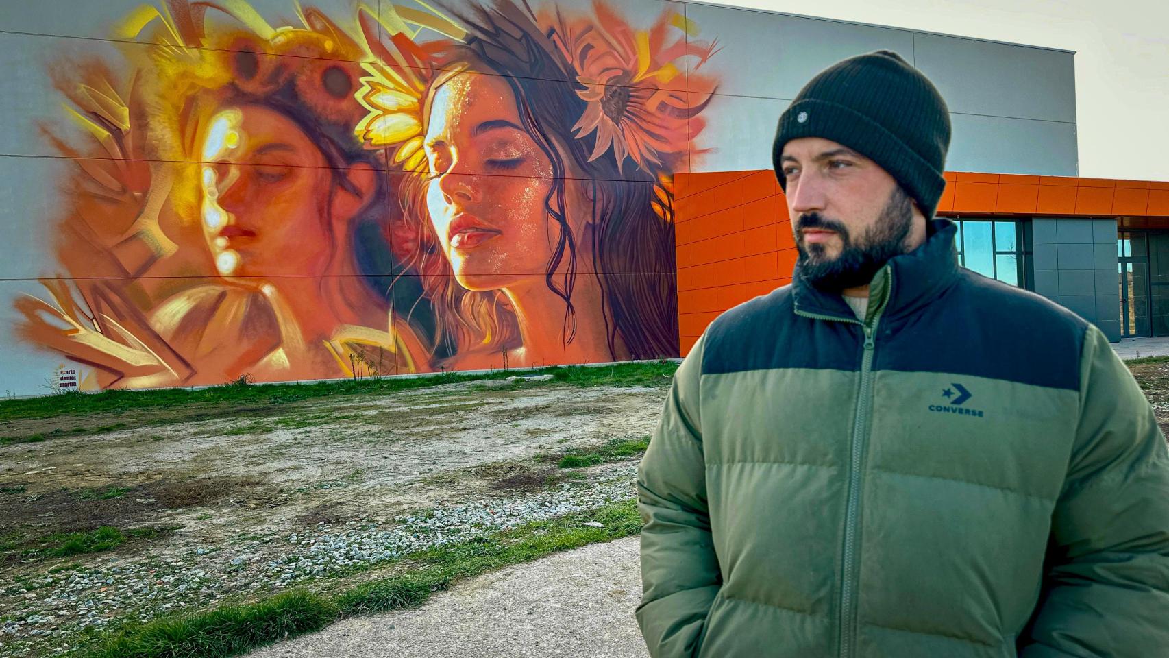 El artista Daniel Martín junto a uno de sus grandes murales