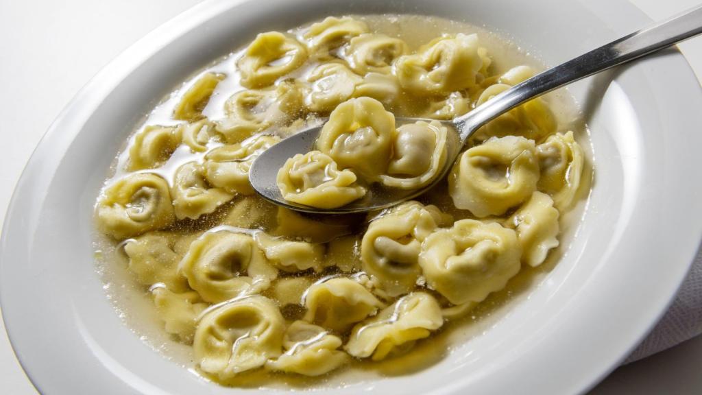 Plato de 'tortellini in brodo' con cuchara.