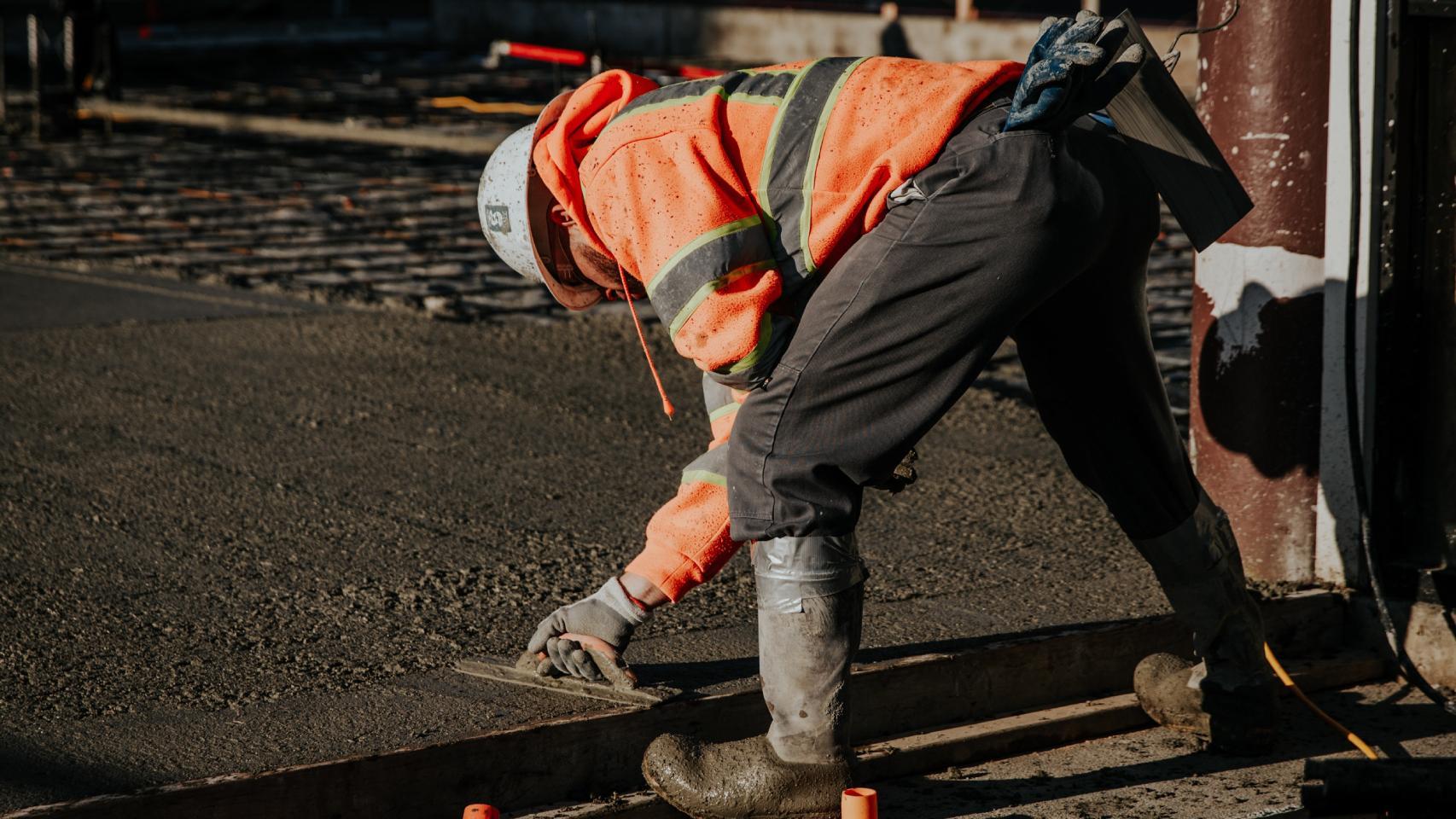 Un trabajador alisando hormigón en una obra al aire libre.